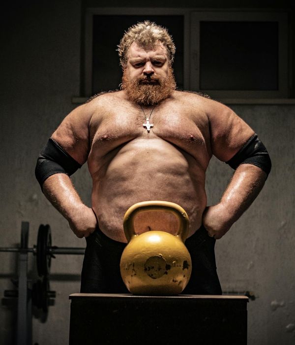 Man performing a powerful bodyweight exercise in a dark gym.